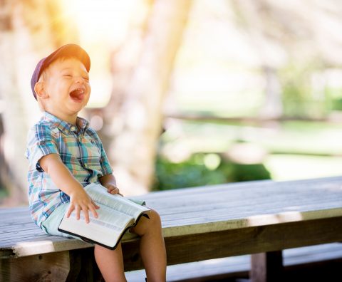 Boy sitting on a bench enjoying reading a good book