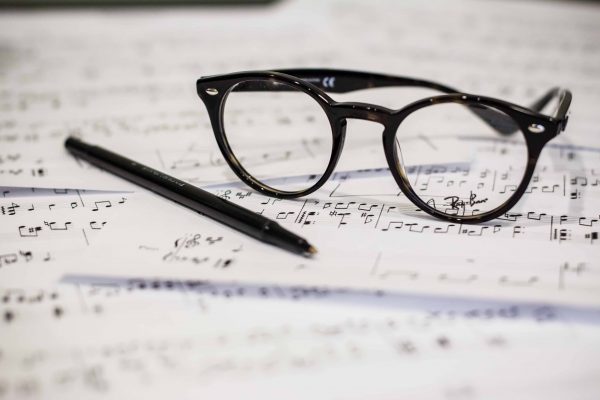 Sheets of music with eyeglasses and a pen on top.